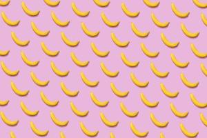 Colorful fruit pattern of fresh yellow bananas on pink background. From top view photo