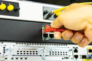 Hand of a man holding The network cables to connect the port of a switch to connect internet network, concept Communication technology photo