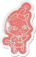cartoon distressed sticker of a cat staring wearing santa hat vector