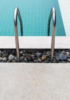 Metal rail of the ladder in the clear swimming pool. photo