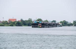 Back view of the convoy of the large cargo boat towed by a tugboat. photo