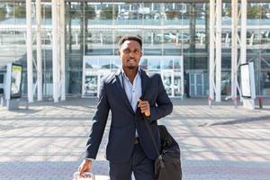 empresario turístico afroamericano camina edificio de transporte público con fondo de equipaje foto