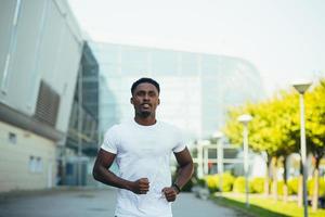 hombre corriendo por la mañana, joven atleta afroamericano corriendo cerca del estadio foto