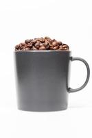 corte los granos de café arábica en una taza negra sobre fondo blanco. foto