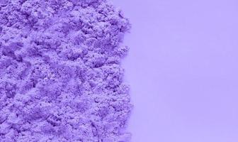 Violet kinetic sand on very peri color paper background with copy space. Early sensory education for children. Kids development concept. Inspired by trendy color of the year 2022 Very Peri. photo