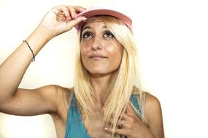 blonde girl in pink hat looks up hands on visor photo