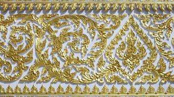 Samut Sakhon, Thailand, 2020 - Traditional golden Kranok pattern on white wall of Wat Chong Lom temple photo