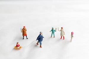 Miniature people Happy family ride a sleigh with snow background photo