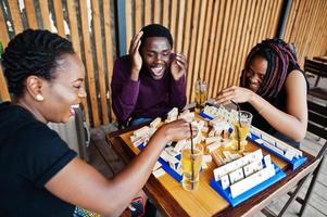 Group of three african american friends play table games. photo