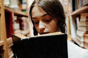 Girl with pigtails in white blouse at old library. photo