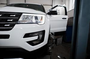 American SUV car on stand for wheels alignment camber check in workshop of service station. photo