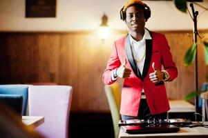 Fashion african american man model DJ at red suit with dj controller, shows thumb up. photo