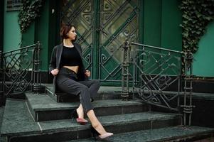 A tall leggy young beautiful and elegant model woman at formal wear posed on stairs. photo