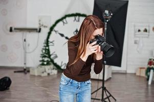 Young girl photographer shooting on studio. Professional photographer on work. photo