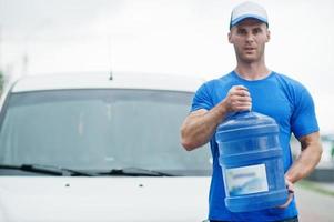 repartidor en camioneta de carga delantera entregando botellas de agua. foto