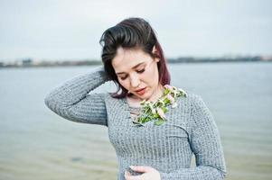 retrato de una chica morena con vestido gris de fondo el lago. foto