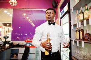 camarero afroamericano en el bar con champán con copas. foto