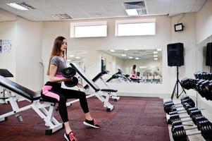 Young brunette sexy slim girl doing workout at gym. photo