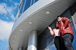 Asian couple standing together against new modern building and look at sky. photo