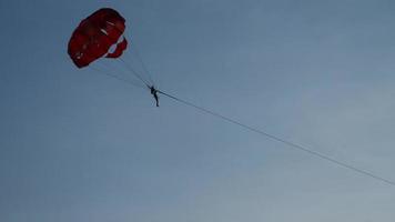Menschen fliegen am Fallschirm weit. Fallschirm fliegt über Wasser. Parasailing im Meer über die Küste. Sommerurlaub Wassersport Freizeit video