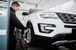 Auto mechanic sets american SUV car for diagnostics and configuration camber check in workshop of service station.. photo