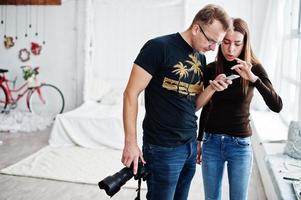 Man photographer with girl looking at mobile phone. Work team discuss something. photo