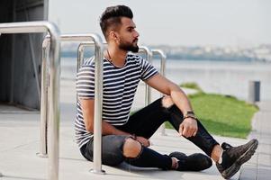 Handsome tall arabian beard man model at stripped shirt posed outdoor. Fashionable arab guy. photo