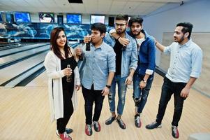 grupo de cinco pueblos del sur de asia descansando y divirtiéndose en el club de bolos. sosteniendo bebidas gaseosas frías de botellas de vidrio. foto