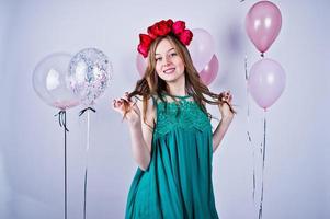 Happy girl in green turqoise dress and wreath with colored balloons isolated on white. Celebrating birthday theme. photo
