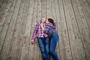 una pareja elegante se viste con una camisa a cuadros enamorada y se acuesta en las tablas. foto