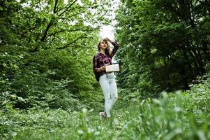 retrato de una joven y hermosa mujer rubia con camisa de tartán sosteniendo un mapa en el bosque. foto