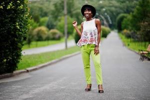 Increíble mujer modelo afroamericana con pantalones verdes y sombrero negro posó con diferentes emociones en el parque. foto