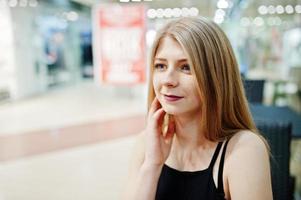 Close up portrait of blonde girl sitting on the mall. photo