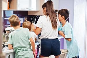 Mother with kids cooking at kitchen, happy children's moments. photo