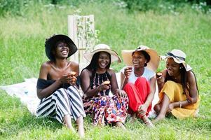 grupo de chicas afroamericanas celebrando la fiesta de cumpleaños y comiendo muffins al aire libre con decoración. foto