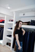 hermosa chica morena en la boutique de la tienda de ropa en ropa casual, camisa negra y jeans. foto