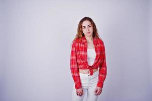 Young girl in red checked shirt and white pants against white background on studio. photo