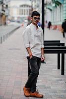 Stylish indian model man in casual clothes and sunglasses posed outdoor at street of India. photo