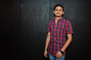 Asian man in checkered shirt against dark background. photo