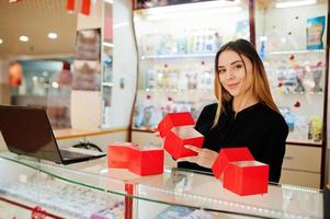 Portrait of young caucasian female woman seller hold red gift boxes. Small business of candy souvenirs shop. photo