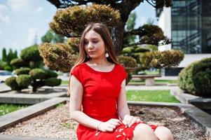 Teenage girl in red dress posed outdoor at sunny day. photo