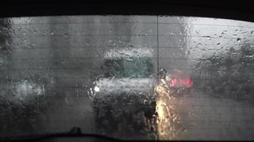View through rainy back window of street traffic and lights video