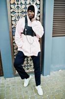 Elegante hombre afroamericano de estilo urbano con capucha rosa posó. rapero afro. foto