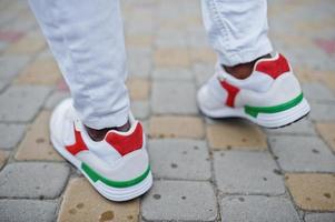 Close up sneakers in african man at white pants. photo