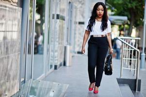Free Photo  Stylish african american business woman with handbag on  streets of city and looking at watches