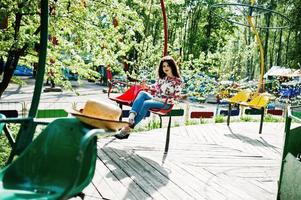 Portrait of brunette girl in pink glasses and hat with ice cream at amusement park. photo