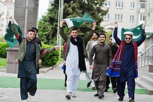 grupo de hombres paquistaníes vestidos con ropa tradicional salwar kameez o kurta con banderas de pakistán. foto