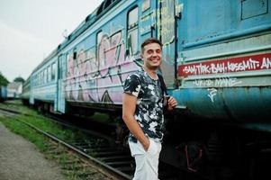 retrato de estilo de vida de un hombre guapo con mochila posando en la estación de tren. foto