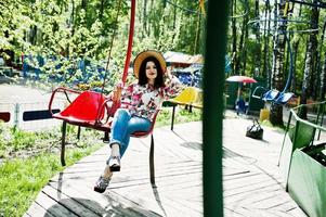 Portrait of brunette girl in pink glasses and hat with ice cream at amusement park. photo