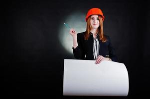 Engineer woman in orange protect helmet with construction paper projekt.